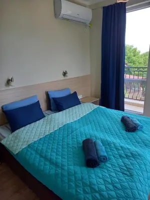 a bedroom with a bed with blue sheets and a window at вила ФЛОРА in Chernomorets