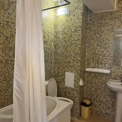 a bathroom with a shower curtain and a toilet and sink at Къща за гости CANAVAN'S in Ravda