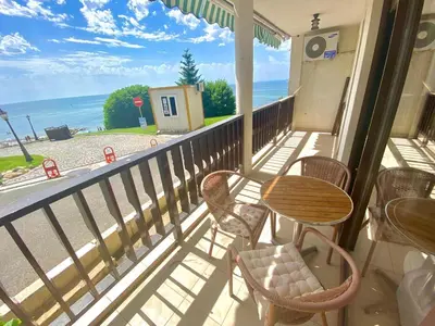 a balcony with tables and chairs and a view of the ocean at Апартамент с фронтална гледка море in Sveti Vlas