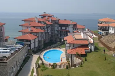 a group of houses with a swimming pool and the ocean at Апартамент с фронтална гледка море in Sveti Vlas