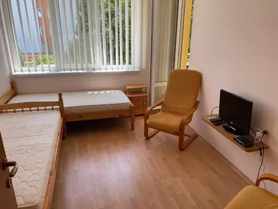 a small room with a bed and a chair and a television at 2-комнатные апартаменты у моря 10 бассейнов Crown Fort Noks in Sveti Vlas