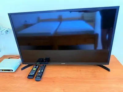 a television screen with two remote controls on a table at 2-комнатные апартаменты у моря 10 бассейнов Crown Fort Noks in Sveti Vlas