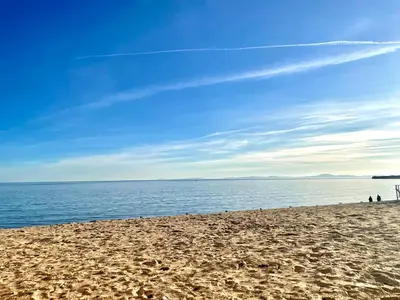 a sandy beach with people standing on it next to the water at Luxury apartment whit sea view at Sunny Beach in Sunny Beach