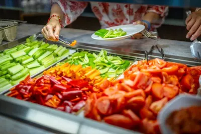 a person cutting up peppers and vegetables on a grill at Galeon Residence & SPA in Sunny Beach