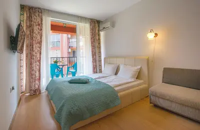 a bedroom with a bed and a window with a chair at Sunny View Central Holiday Apartments in Sunny Beach