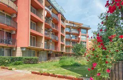 an apartment building with red flowers in front of it at Sunny View Central Holiday Apartments in Sunny Beach