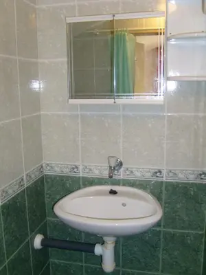a green tiled bathroom with a sink and a mirror at Сотирови, самостоятелни стаи in Chernomorets