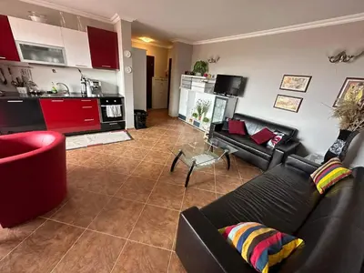 a living room with a black couch and a kitchen at Sirena in Sveti Vlas