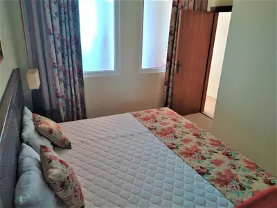 a bedroom with a bed with a flower blanket on it at Апартамент Сънсет Ризорт in Pomorie