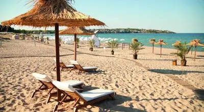 a beach with chairs and umbrellas and the ocean at Paradise Dreams - Bulharske More - Sveti Vlas in Sveti Vlas