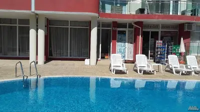 a group of chairs and a swimming pool in front of a building at Глобал вил in Sunny Beach