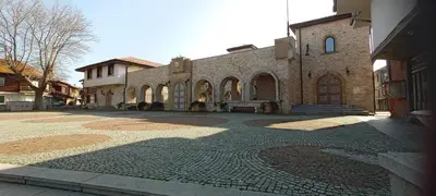 a large brick building with a stone courtyard at Глобал вил in Sunny Beach