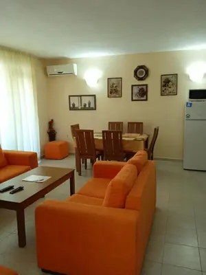 a living room with an orange couch and a table at Big comfortable apartment with 2 bedrooms Pollo Resort Sunny Beach in Sunny Beach