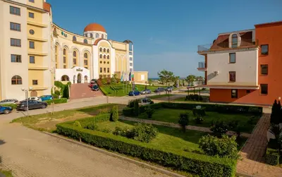 a building with a garden in front of a street at ADIRAMAR Apartments in Obzor