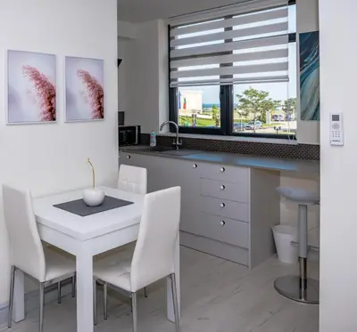 a kitchen with a white table and chairs and a window at ADIRAMAR Apartments in Obzor