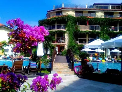 a building with purple flowers next to a swimming pool at Апартамент Лагуна Aйланд in Sozopol