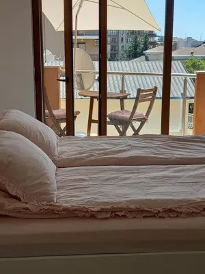 a bed with an umbrella and a table and chairs at Perla 1 apartments in Ravda