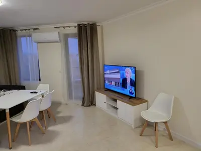 a living room with a tv and a table and chairs at Apartment on the beach 2 in Ravda