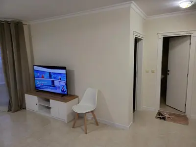 a living room with a tv and a white chair at Apartment on the beach 2 in Ravda