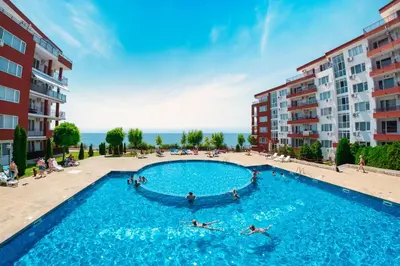a large swimming pool with people in it next to buildings at Panorama Fort Beach in Sveti Vlas