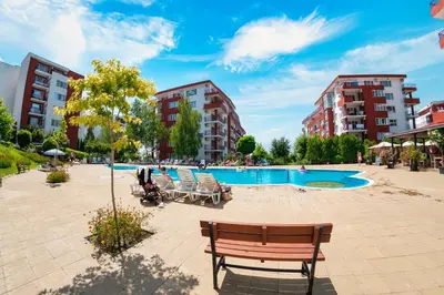 a swimming pool in a park with chairs and buildings at Marina View Fort Beach in Sveti Vlas