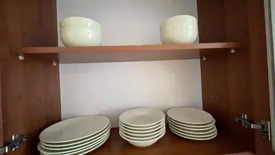 three plates and bowls on a shelf in a cabinet at ANITA C 19 Apartment Sunny Beach in Sunny Beach