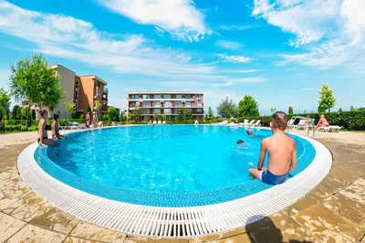 a group of people sitting around a swimming pool at Orchid Fort Garden in Sunny Beach