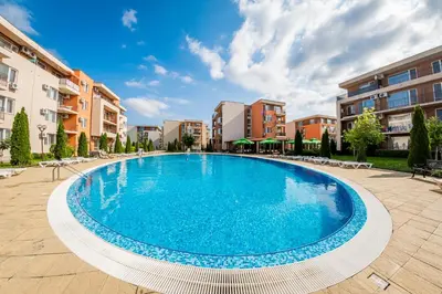 a large swimming pool in a courtyard with buildings at Orchid Fort Garden in Sunny Beach