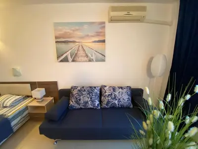 a living room with a blue couch and a painting at ESPERANTO 402 Large Studio Sunny Beach in Sunny Beach