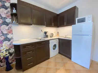 a kitchen with brown cabinets and a white refrigerator at Cascadas Family Resort - Private apartment - BSR in Sunny Beach