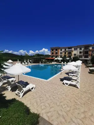 a swimming pool with lounge chairs and umbrellas at Lily Beach - Apartment 408A in Sozopol