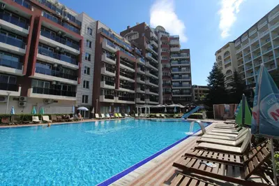a large swimming pool with lounge chairs and apartment buildings at Menada Admiral Plaza Apartaments in Sunny Beach