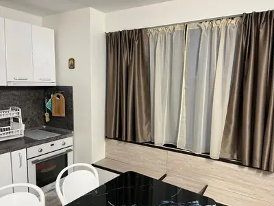 a kitchen with a window with curtains in it at Апартамент Холи in Sozopol
