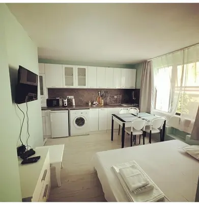 a kitchen with a table and chairs in a room at Апартамент Холи in Sozopol