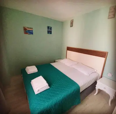 a bedroom with a large bed with a green blanket at Апартамент Холи in Sozopol