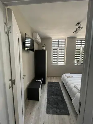 a bedroom with a bed and a table and windows at Dream in Varna City