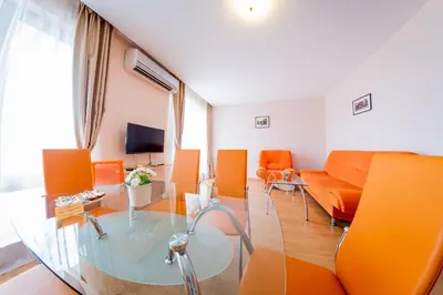 a living room with orange chairs and a glass table at Prestige Mer d'Azur in Sunny Beach