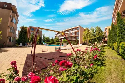 a playground with flowers in front of a building at Holiday Garden Resort in Sunny Beach