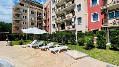 a patio with chairs and an umbrella in front of a building at Bratanov Vip Zone maisonettes 606 & 609 in Sunny Beach