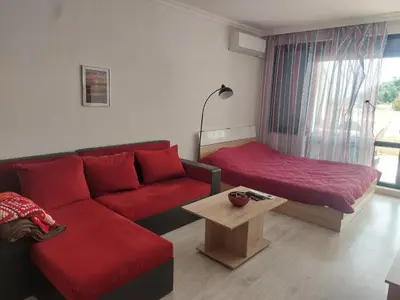 a living room with a red couch and a table at Studio Sarafovo in Burgas City
