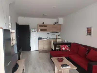 a living room with a red couch and a kitchen at Studio Sarafovo in Burgas City