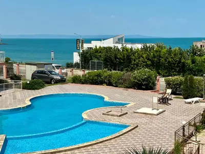 a blue swimming pool with the ocean in the background at Private One-Bedroom Apartment with Balcony in Sozopol by Flat Mаnаger in Sozopol