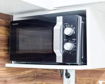 a black microwave oven on a shelf in a kitchen at Aleks Sunrise -Top Center ,Sea Garden in Burgas City