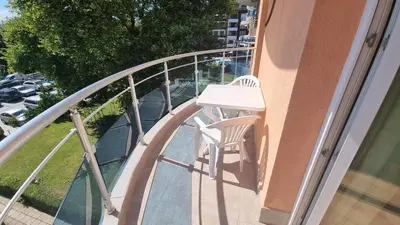 a white chair sitting on the balcony of a building at Oasis deluxe apartment by the sea in Ravda