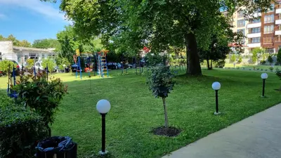 a park with a playground with a tree in the grass at Oasis deluxe apartment by the sea in Ravda