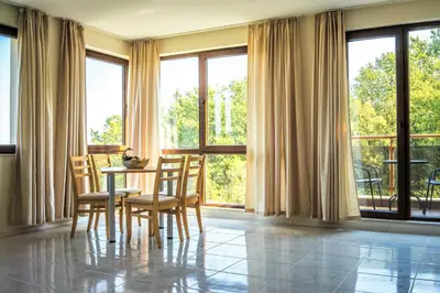 a dining room with a table and chairs and windows at Moreto Seaside Aparthotel in Obzor