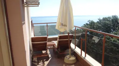 a balcony with chairs and an umbrella and the ocean at Moreto Seaside Aparthotel in Obzor