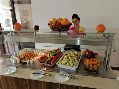 a woman behind a counter with fruits and vegetables at Moreto Seaside Aparthotel in Obzor