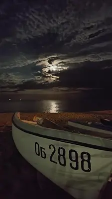 a boat sitting on the beach with the sunset at Moreto Seaside Aparthotel in Obzor