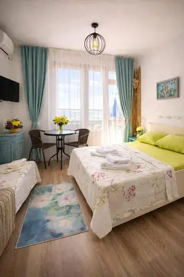 a bedroom with two beds and a table with chairs at Guest house Hei taka in Sozopol